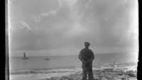 Object Photograph of An Aran Island man on the shoreline watching a four-man crew in a currach approaching a Galway Hooker to collect turfcover picture